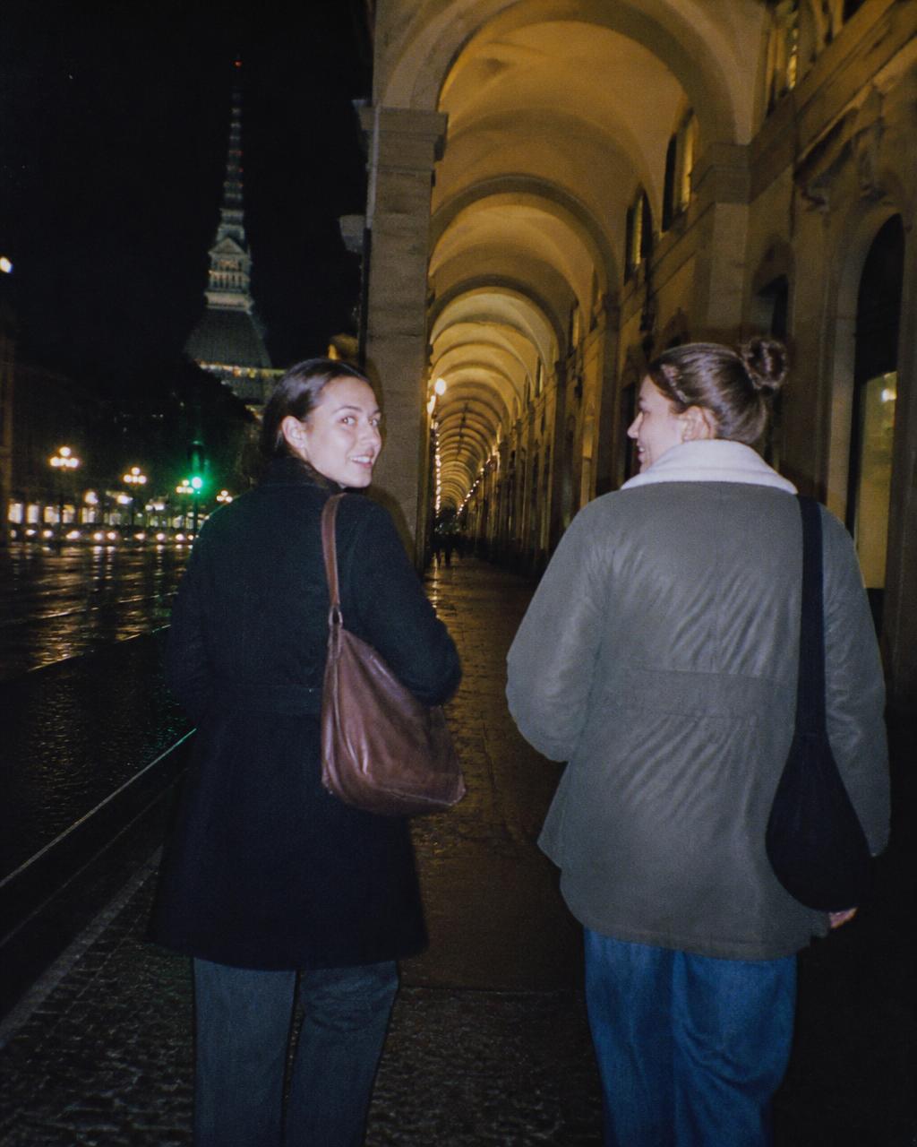 Due amiche camminano sotto i portici di Torino